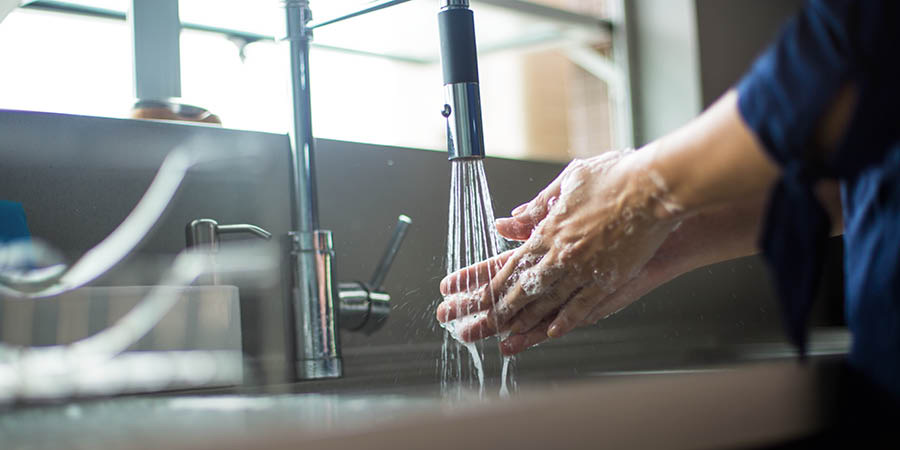 Una mujer lavándose las manos con agua y jabón.