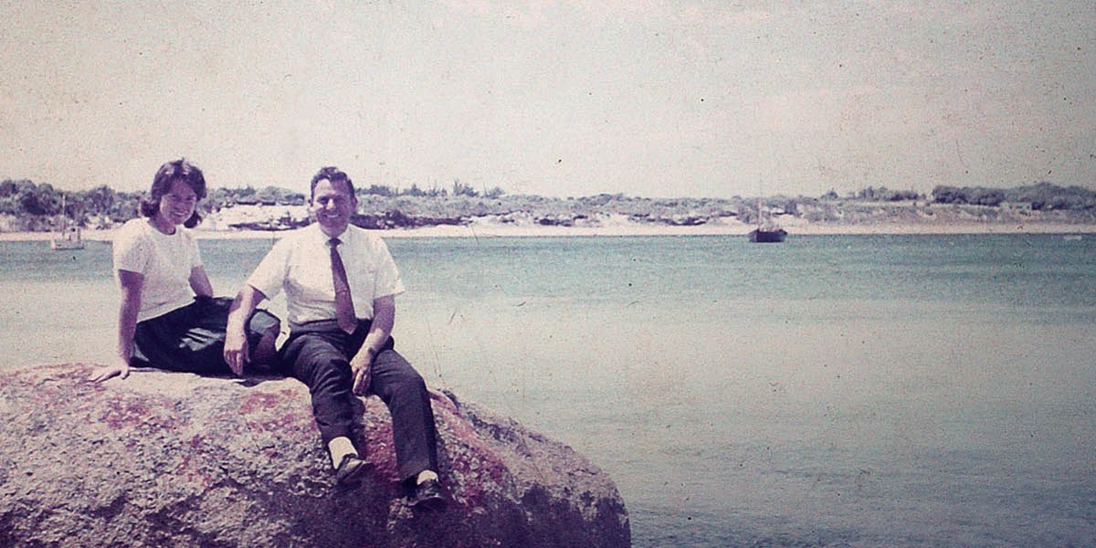 Pamela y Winston Payne, de jóvenes, sentados sobre una roca junto al mar