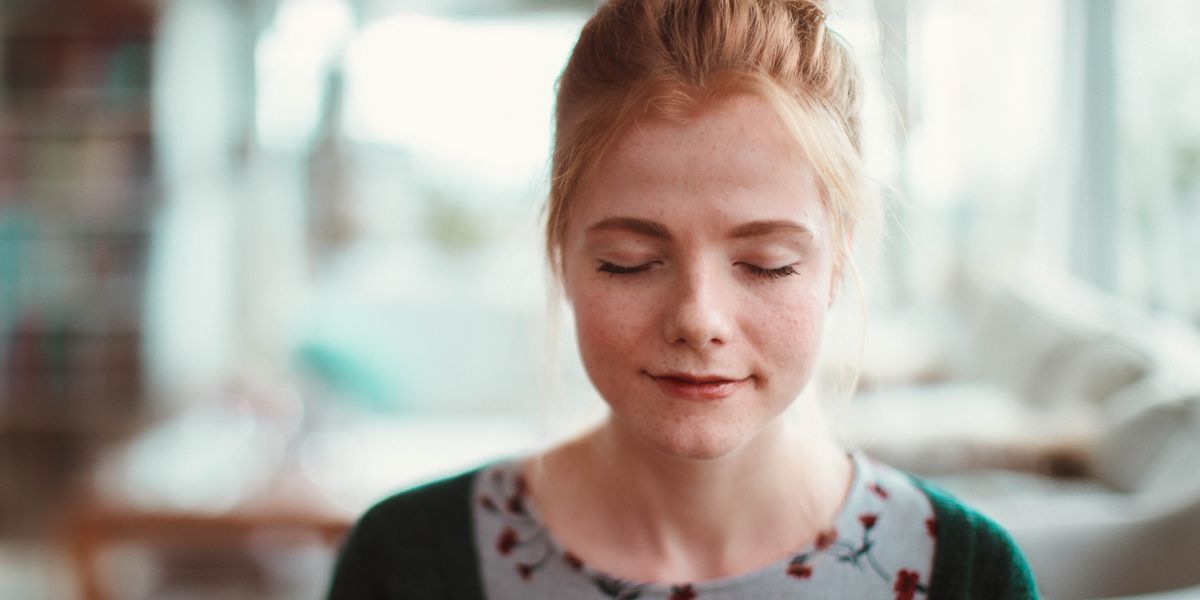 A young woman peacefully praying in her home.