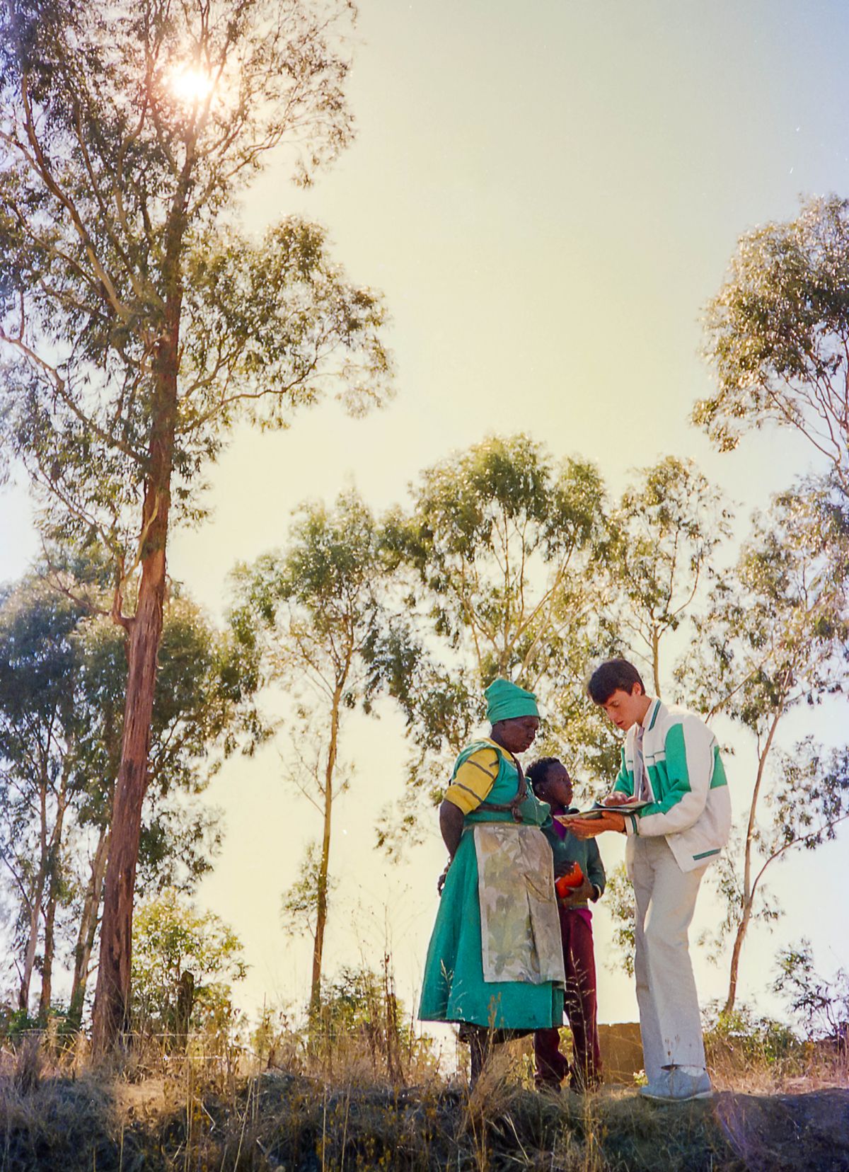 A white brother witnessing to a black woman and her young son in a rural area.