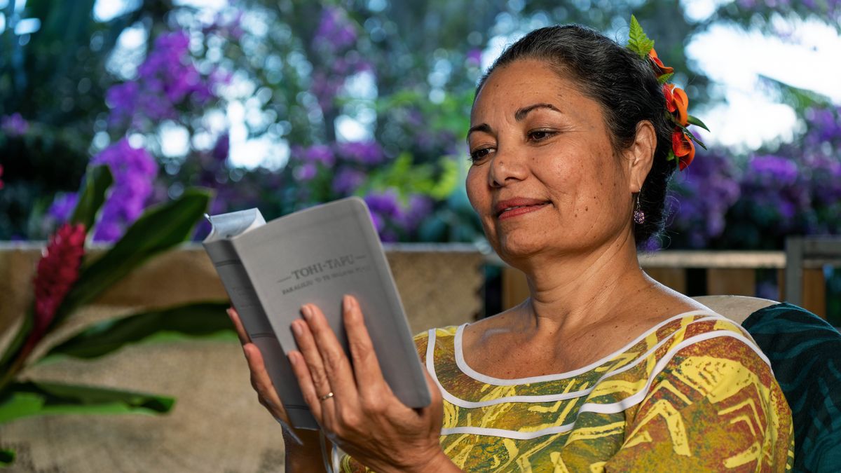 A sister reading from a printed copy of the “New World Translation of the Holy Scriptures” in her native tongue, Wallisian.