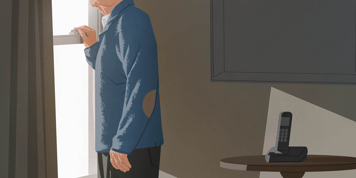 An elderly man looking out the window by his phone.