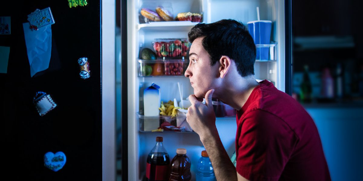 A young man decides which foods to eat from a refrigerator