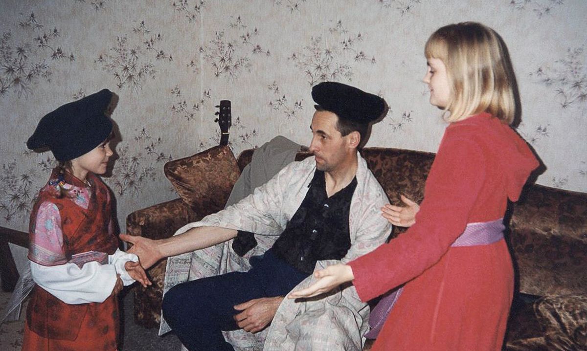 Virgilijus wearing a hat as a crown and a blanket as a robe, as he and his two daughters act out a scene from the Bible book of Esther.