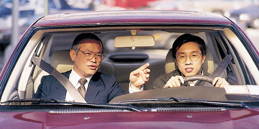 A man drives a car while an instructor guides him