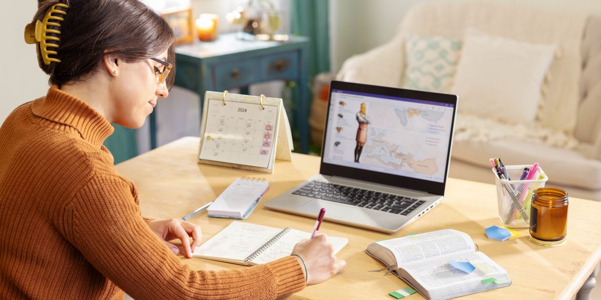 A sister using a laptop computer, a Bible, and a notebook to do personal Bible study. She uses the chart “World Powers Foretold by Daniel” in Appendix B9 of the “New World Translation.”