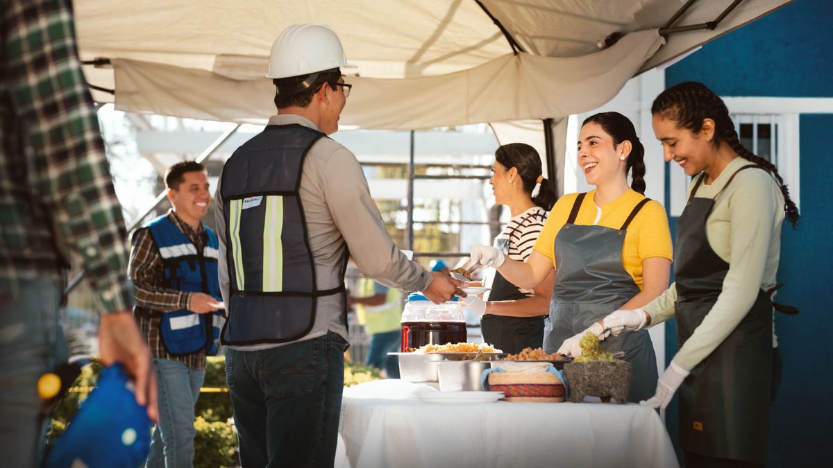 Three sisters cheerfully serving food to brothers at a theocratic construction project.