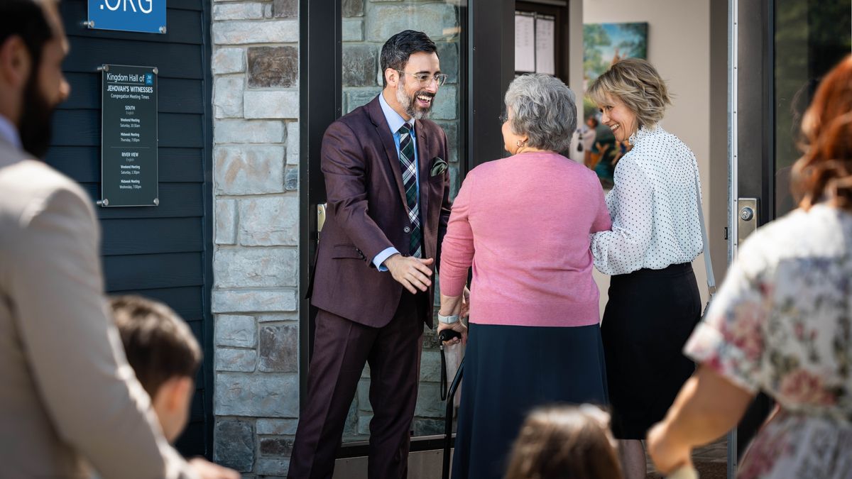 At a future meeting, the brother cheerfully holds the Kingdom Hall door open for an older sister and another sister.