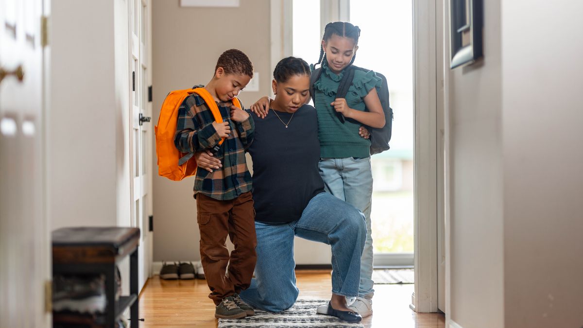 A mother kneels and prays with her two children before they leave for school.