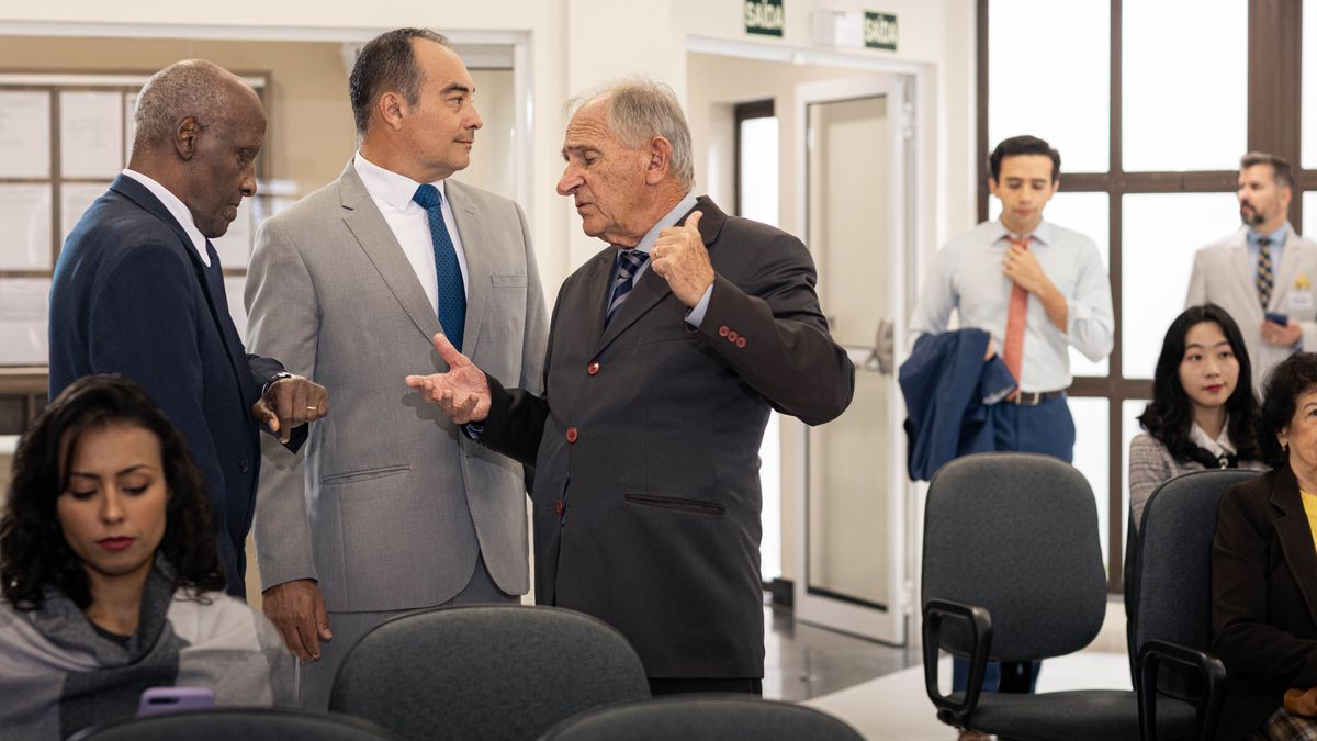 The elder listens to two of his fellow elders speak negatively about the young brother who is rushing into the Kingdom Hall as the meeting starts.