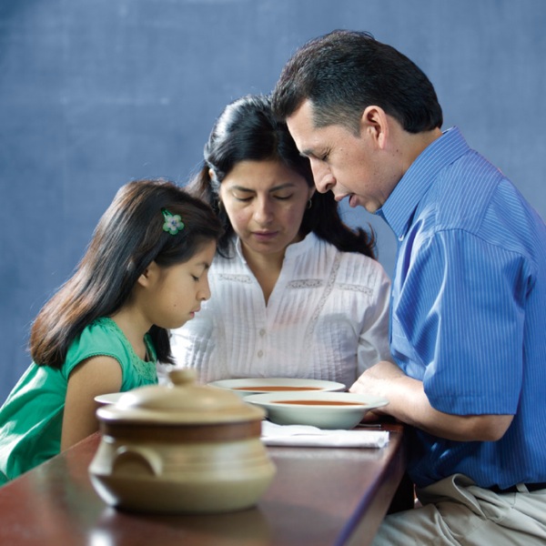 A Witness family praying to Jehovah God before a meal