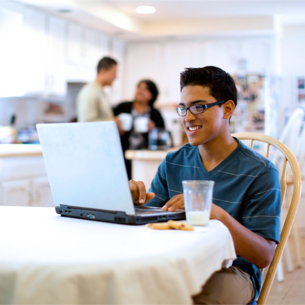 Un joven utilizando su computadora en un área de la casa que toda la familia usa