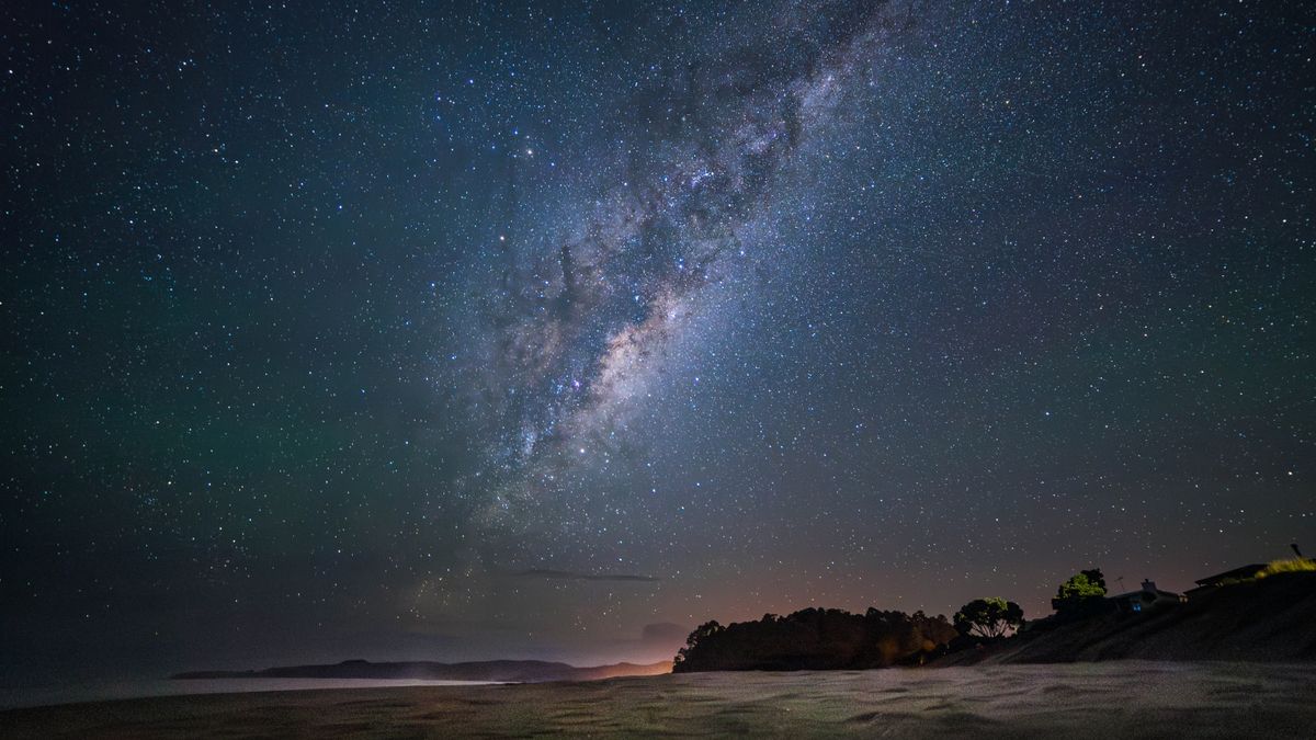 Un cielo lleno de estrellas sobre la arena de una playa.