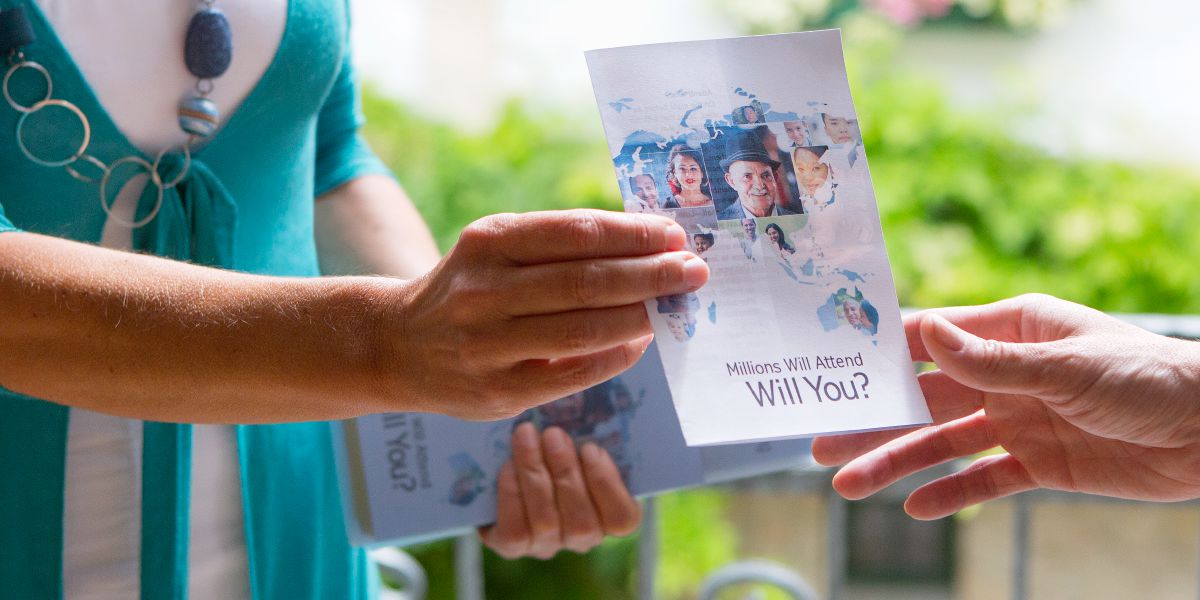 Una testigo de Jehová entrega una invitación a una mujer