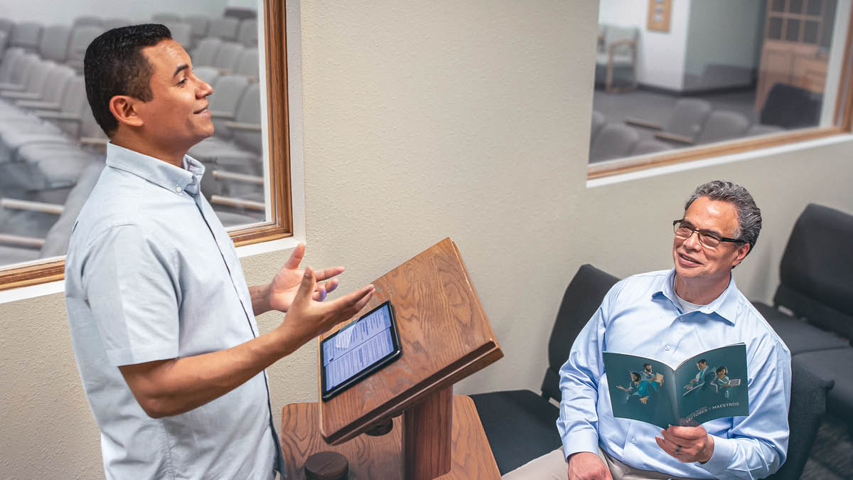 پیر جماعت به برادری که سخنرانی‌اش را تمرین می‌کند گوش می‌کند.‏ آن پیر بروشور «خواندن و تعلیم» در دست دارد.‏ 