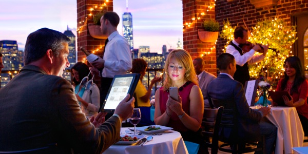 Un homme et sa femme dînant au restaurant utilisent leurs appareils électroniques au lieu de se parler