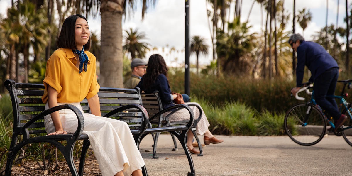 Dans un jardin public, une femme assise sur un banc réfléchit