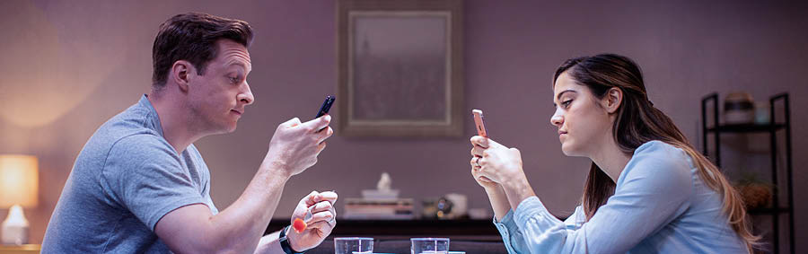 Des conjoints qui prennent un repas ensemble sont tous les deux absorbés pas leur smartphone.