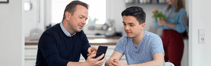 Un père enseigne à son fils à se servir d’un smartphone de manière responsable.