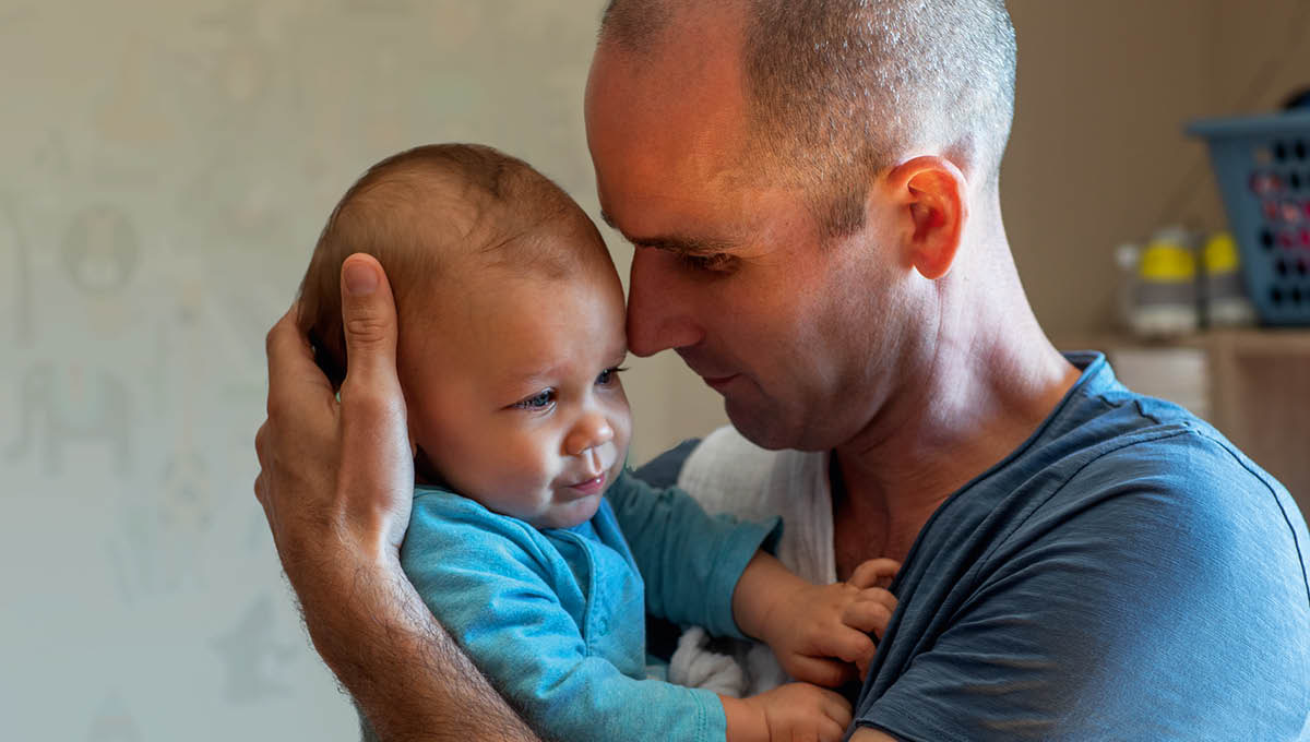 Un jeune papa berce son bébé.