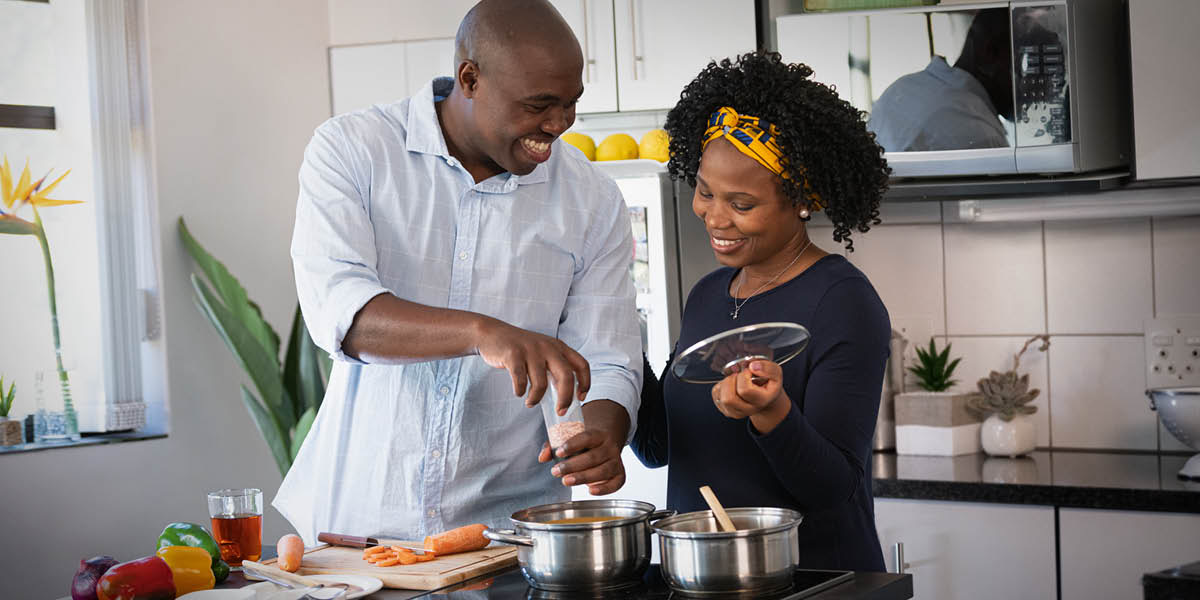 Un mari et sa femme préparent joyeusement le repas ensemble.