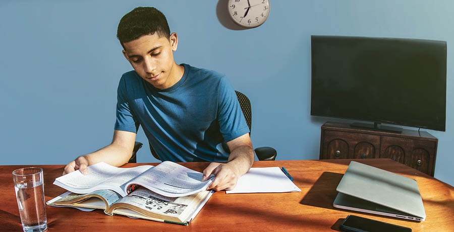 Un adolescent fait ses devoirs tôt dans la soirée et sans sources de distraction.