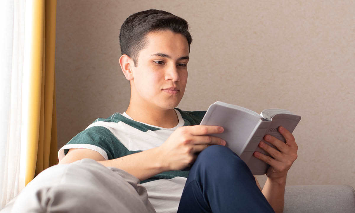 Le même garçon lit la Bible.