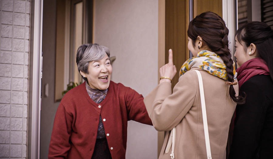 La pionnière et une autre sœur saluent la dame chez qui elles arrivent pour lui donner un cours biblique.