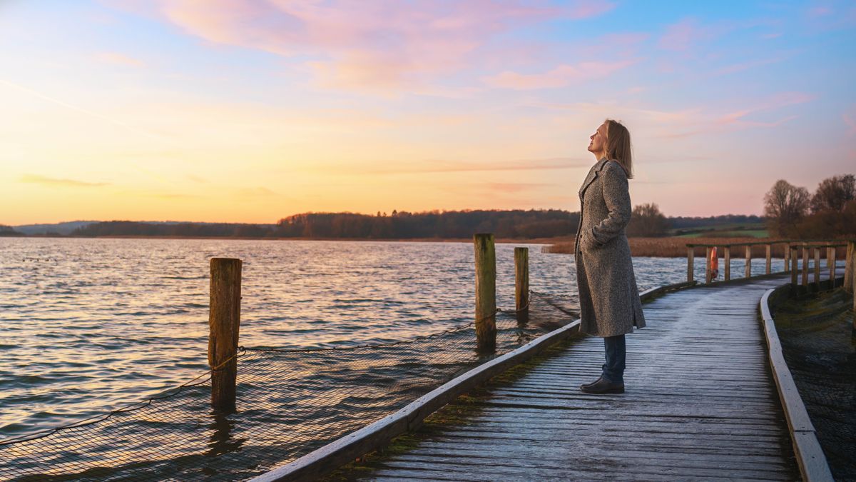 Une femme se tenant sur un ponton regarde vers le ciel.