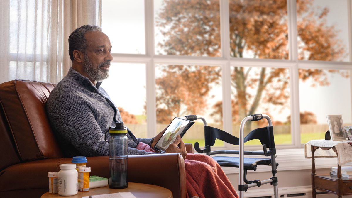 Le frère âgé est chez lui, assis dans son fauteuil. C’est l’automne. Il réfléchit à l’image du paradis qui est affichée sur sa tablette. À côté de lui, il y a un déambulateur et plusieurs flacons de médicaments.