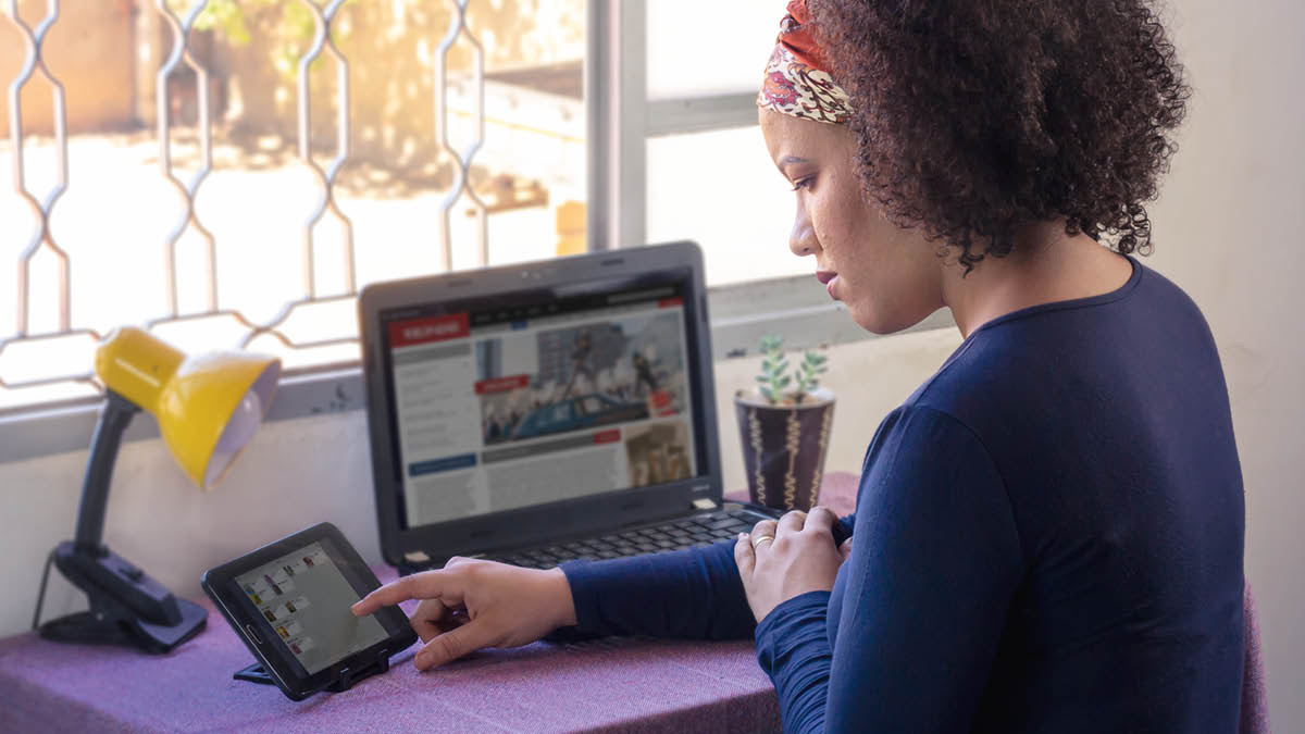 Eine Schwester bereitet sich auf den Dienst vor. Sie hat ein Traktat in der Hand und liest auf ihrem Computer die aktuellen Nachrichten.