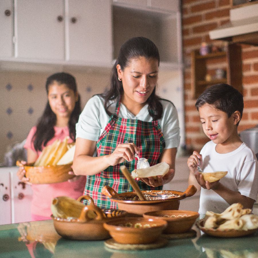 Una madre y sus hijos preparan alimentos para sus invitados