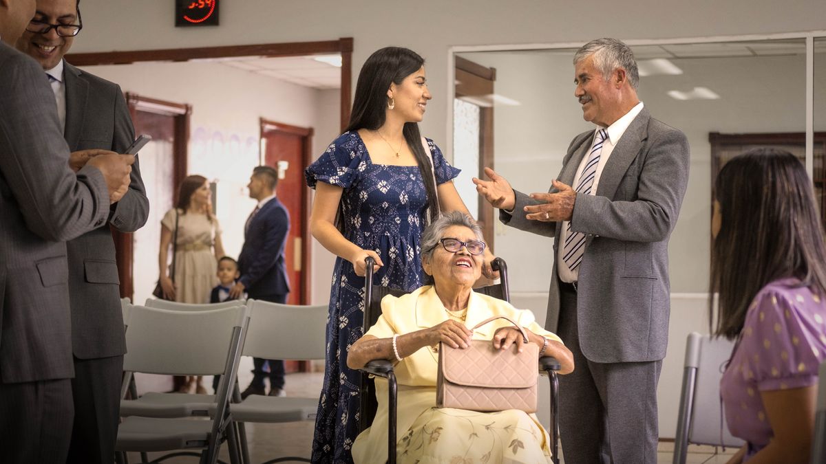 Un anciano felicita a una hermana que está ayudando a otra, que va en silla de ruedas.