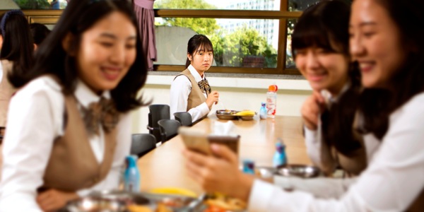 એક છોકરી એકલી બેસીને બીજી છોકરીઓને વાતચીત કરતા જોઈ રહી છે