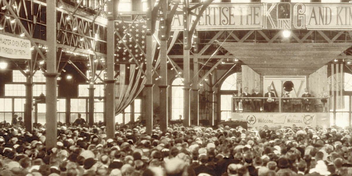Pe platafórma asambleahápe áño 1922-pe. Pe yvate oĩ pe letréro heʼíva: “¡Peikuaauka mávapa pe Rréi ha irréino!”. Pe platafórma fóndope ojekuaa umi létra “ADV”.