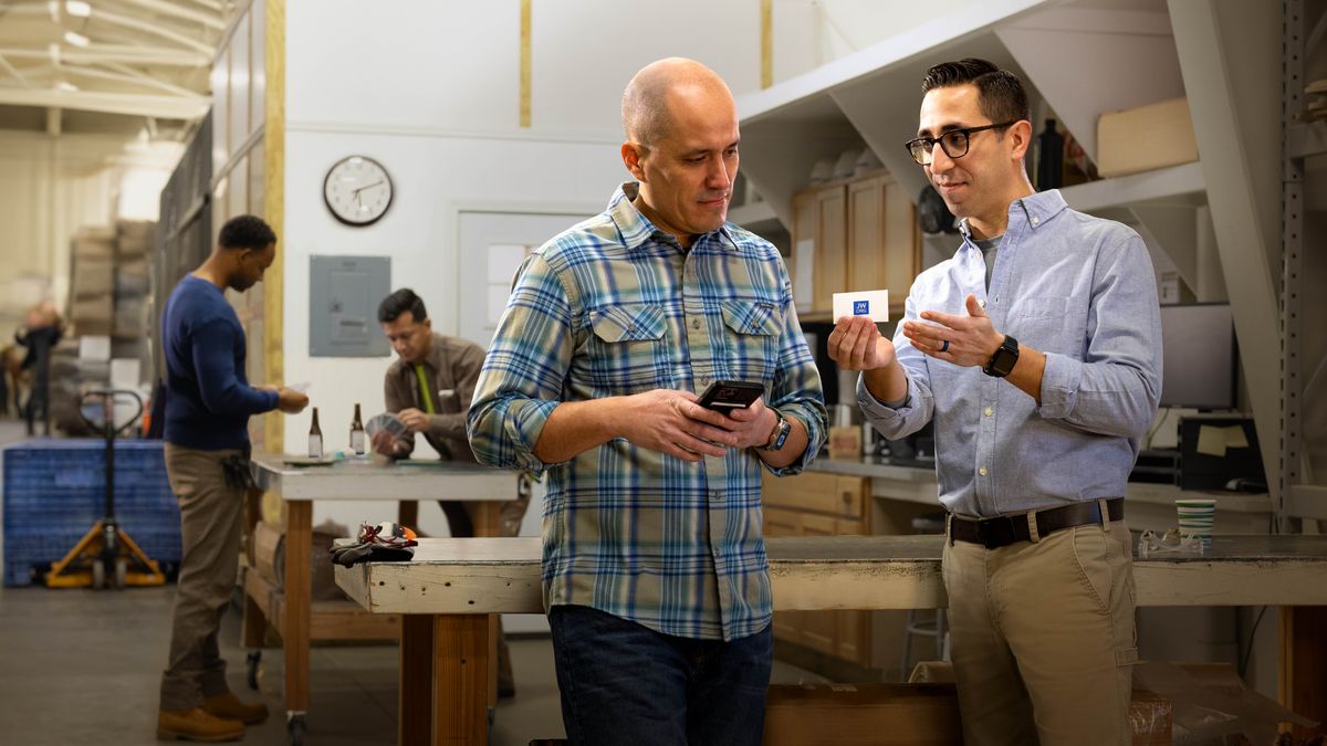 Egy testvér ad egy jw.org-os kártyát a kollégájának a munkahelyi szünetben.