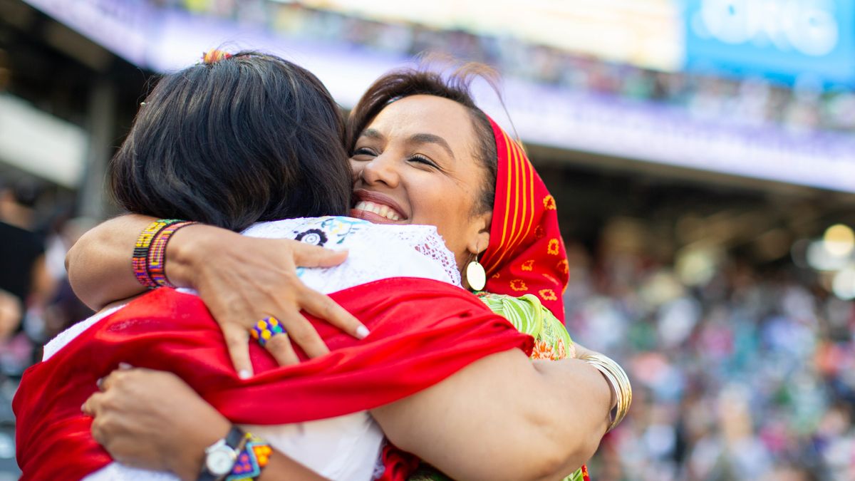 Two sistahs hugging each odda at one big kine meeting.