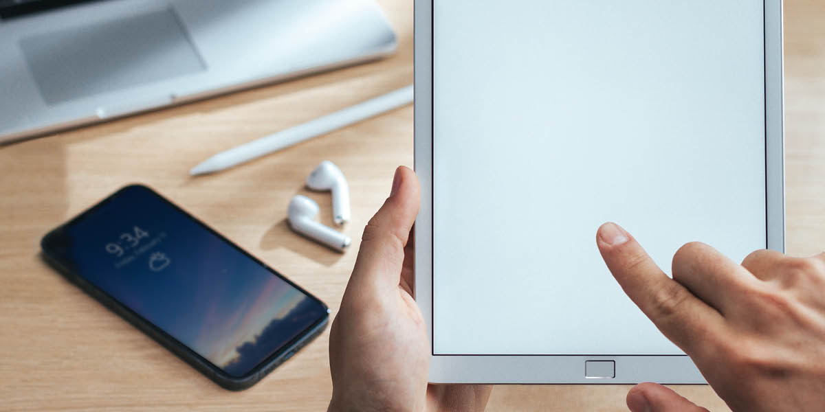 Ebe mmadụ na-apị tablet. Kọmputa na ekwentị dịkwa n’elu tebụl dị ebe ahụ.