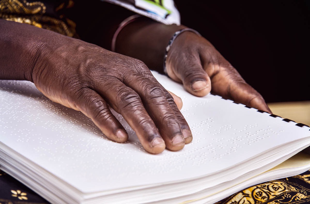 Seorang saudari yang tunanetra menggunakan jari-jarinya untuk membaca publikasi Braille.