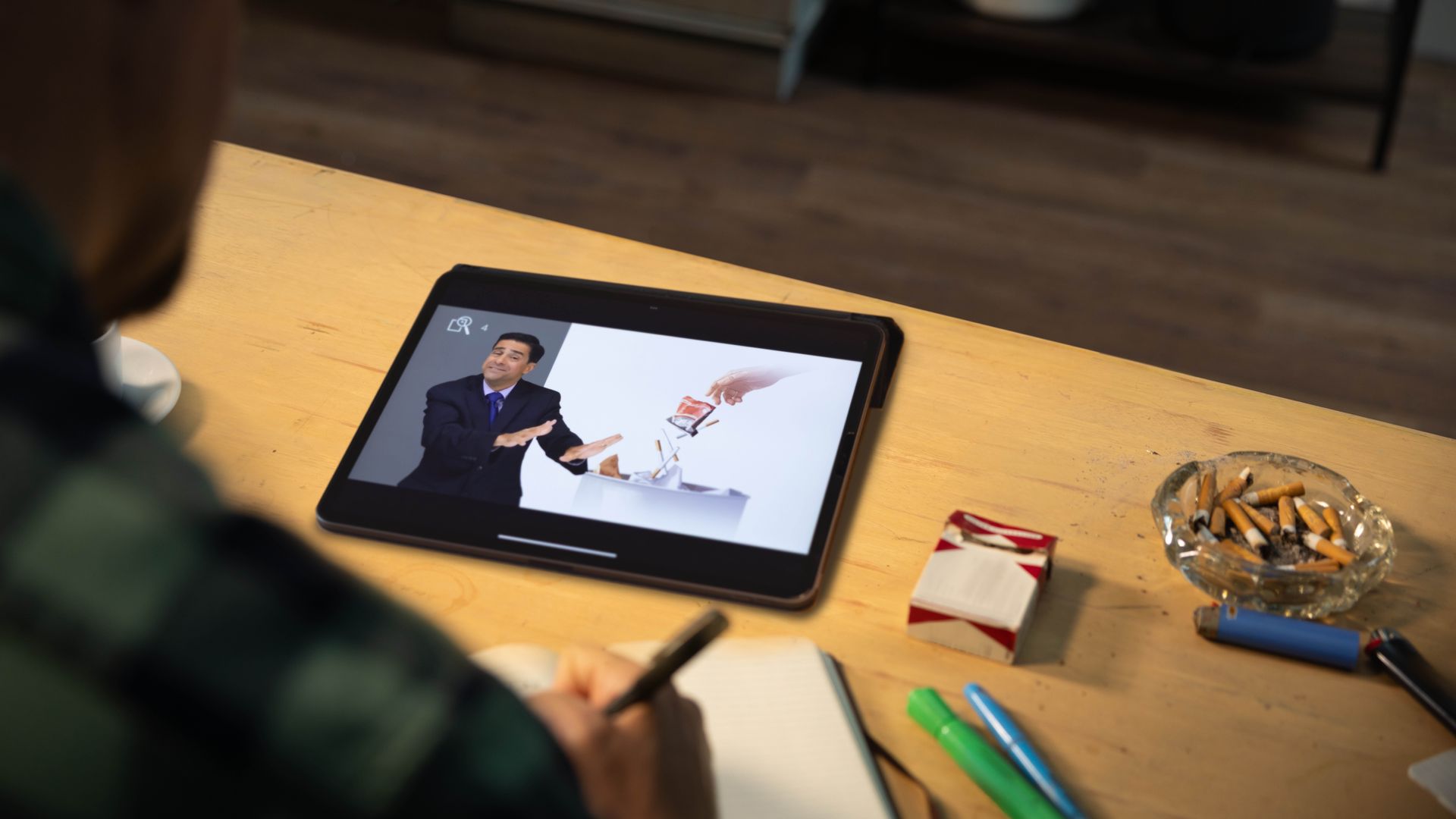 Seorang pria sedang membaca pelajaran 40 dari buku ”Hidup Bahagia Selamanya!” Di mejanya, ada sebungkus rokok dan asbak yang penuh dengan puntung rokok.