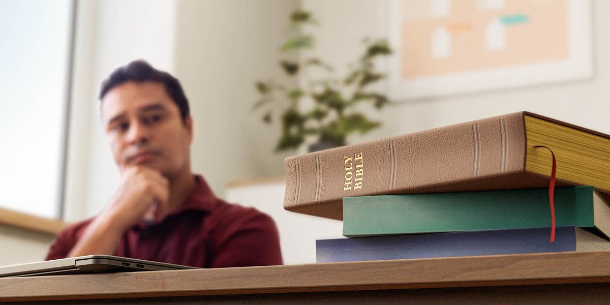 Maður íhugar biblíuvers og er með fleiri bækur á skrifborðinu.