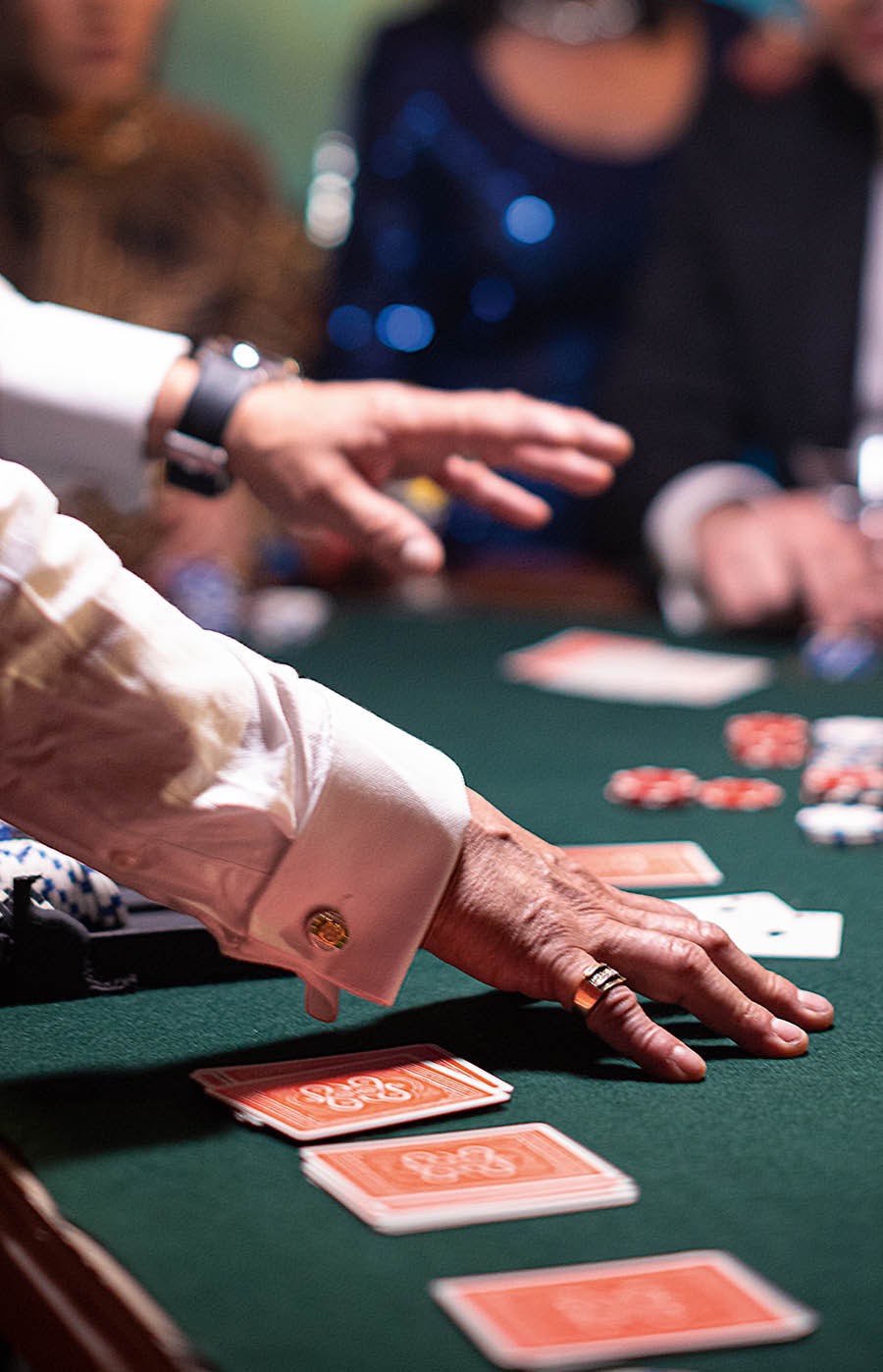 Un uomo dà le carte a un tavolo da gioco di un casinò mentre i giocatori osservano.