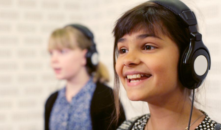 Two girls sing in a recording studio