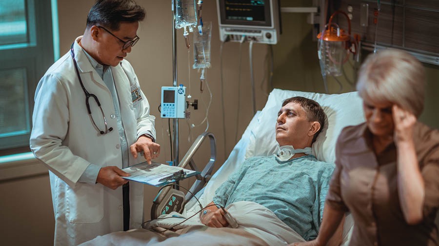 L’uomo raffigurato precedentemente è disteso sul letto di un ospedale. Sua moglie è disperata quando sente la cattiva notizia del dottore.