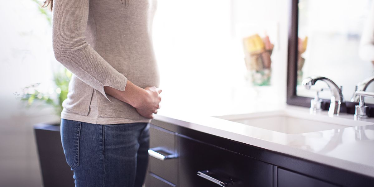 Una donna incinta in piedi davanti allo specchio