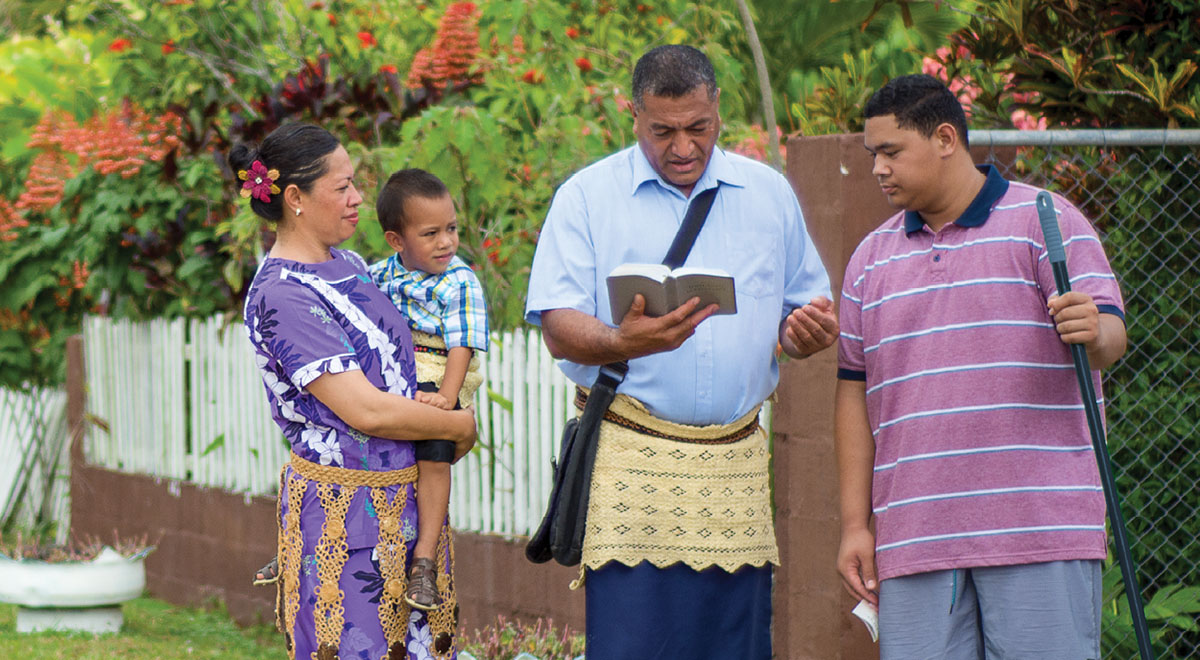 Solomone Tonga con la sua famiglia mentre predica a un uomo