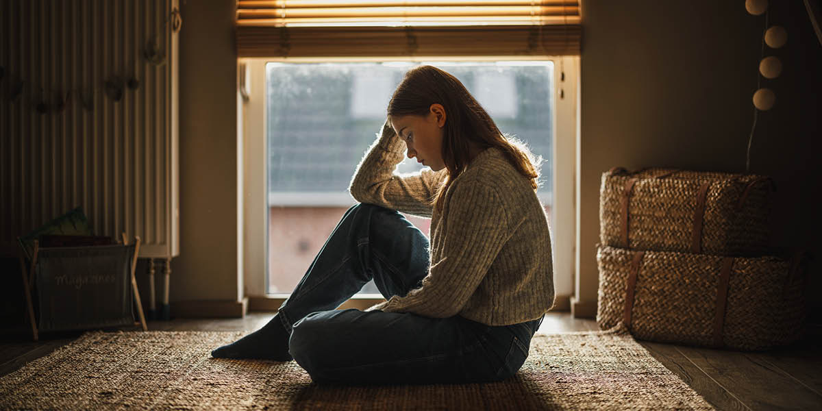 Una ragazzina fissa con aria triste il pavimento.