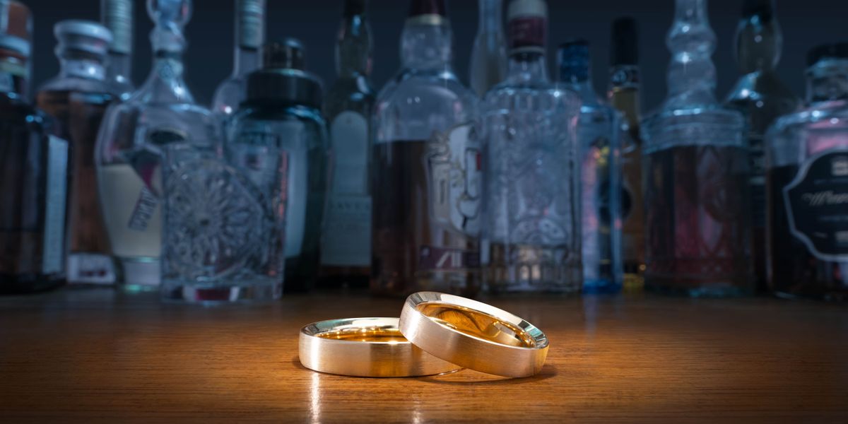 Due fedi nuziali e varie bottiglie di alcol su un tavolo.