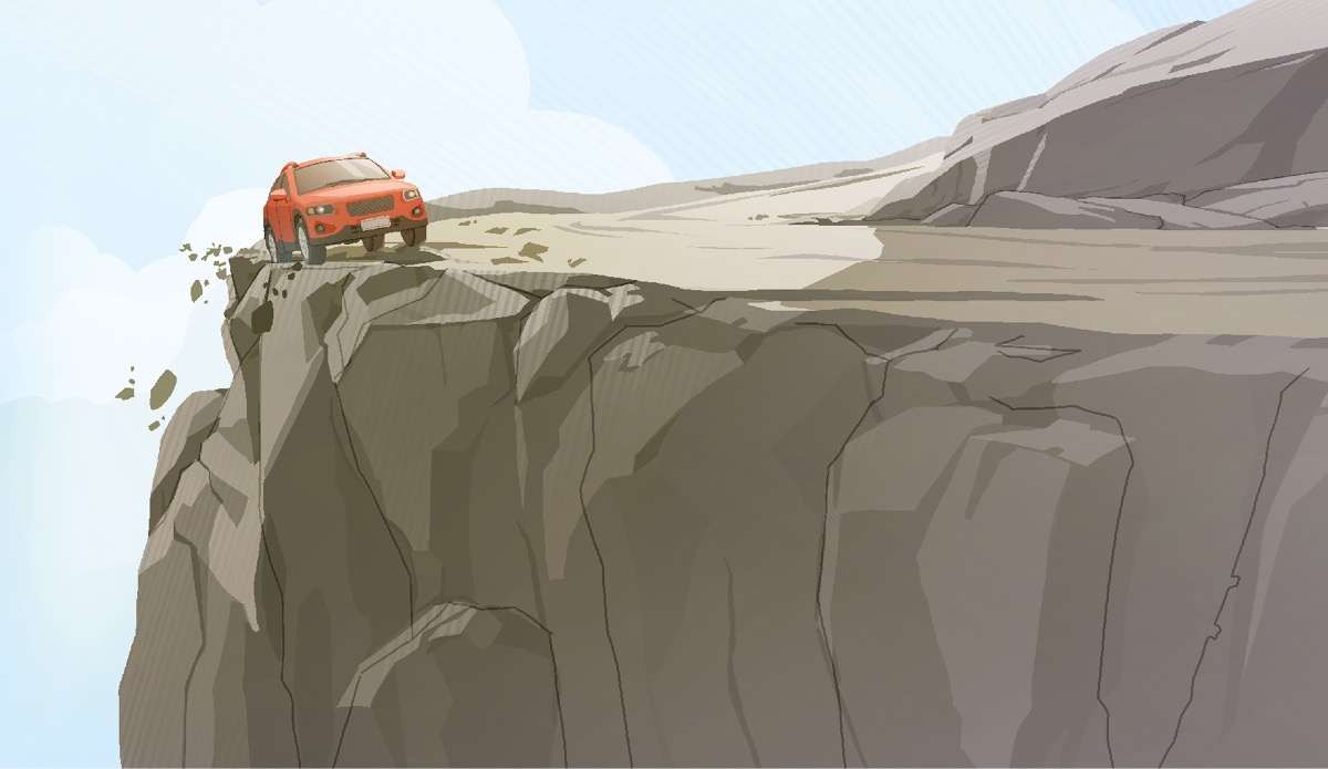 Un’auto passa vicino al ciglio di una strada di montagna. Le ruote posteriori sono già fuori strada.