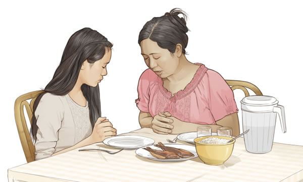 Una madre pronuncia una preghiera con la figlia prima di mangiare